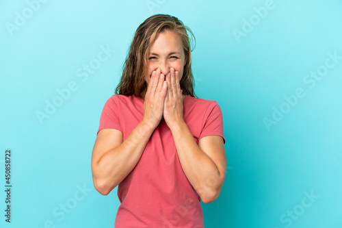 Young caucasian woman isolated on blue background happy and smiling covering mouth with hands