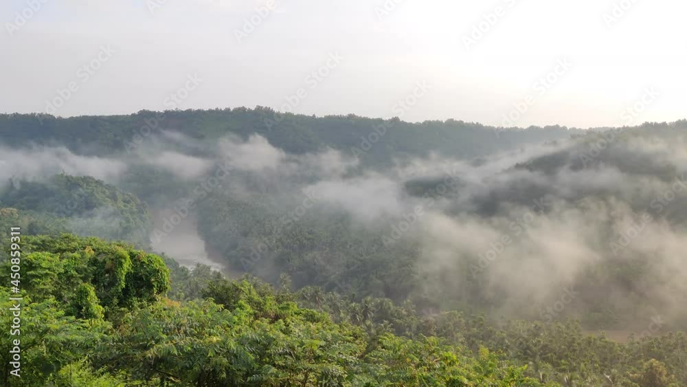 Early morning mist lingering in the valley and hills. The long flowing river separates the hills. This stunning video was taken from a place called Karicheri View point Kerala India Early morning mist lingering in the valley and hills. The long flowing river separates the hills. This stunning video was taken from a place called Karicheri View point Kerala India