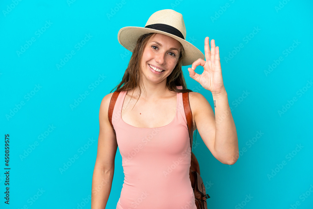 Young caucasian woman in summer holidays isolated on blue background showing ok sign with fingers Young caucasian woman in summer holidays isolated on blue background showing ok sign with fingers