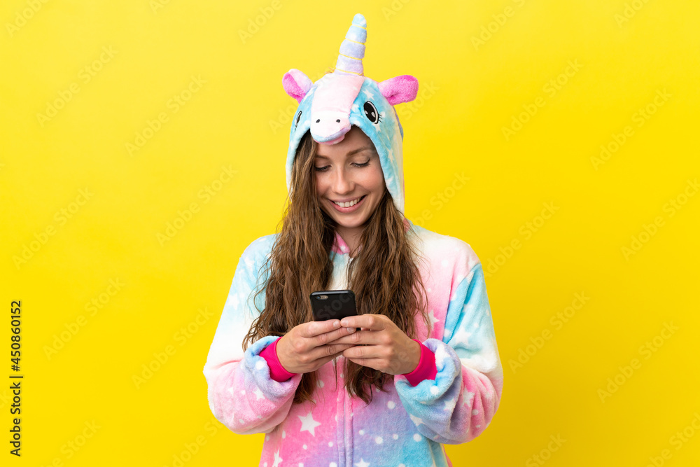 Girl with unicorn pajamas over isolated background sending a message with the mobile Girl with unicorn pajamas over isolated background sending a message with the mobile