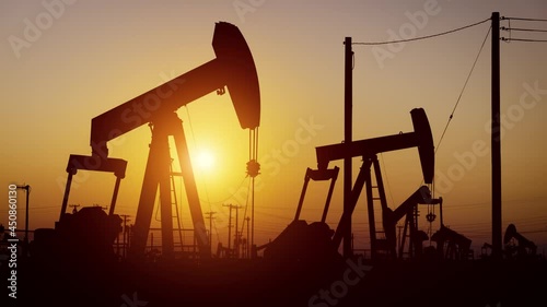 The sun rises behind oil pumps in California