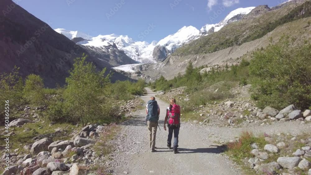 Two friends during an alpine trek towards a glacier. In the Swiss Alps