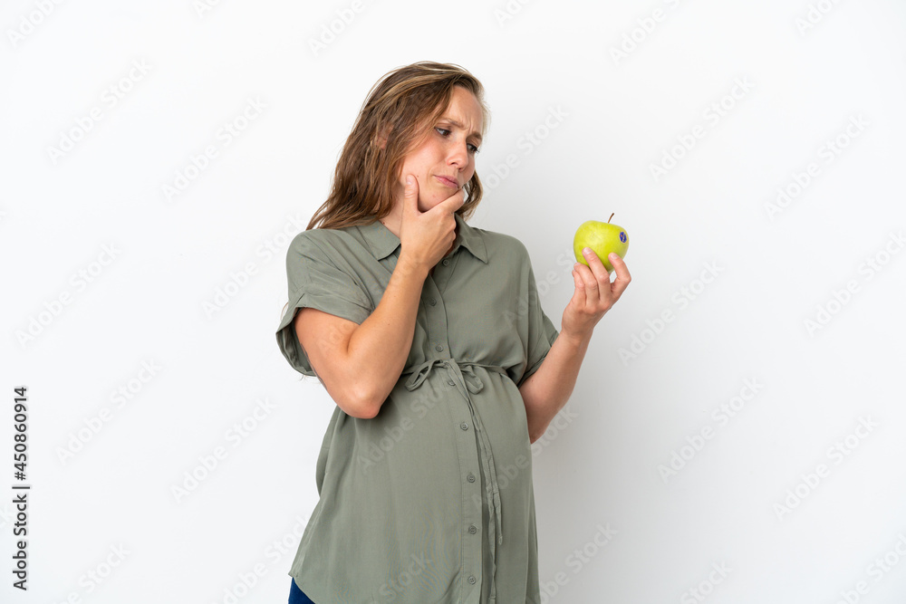 Young caucasian woman isolated on white background pregnant and holding an apple while thinking Young caucasian woman isolated on white background pregnant and holding an apple while thinking