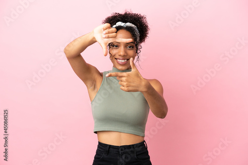 Young latin woman isolated on pink background focusing face. Framing symbol © luismolinero