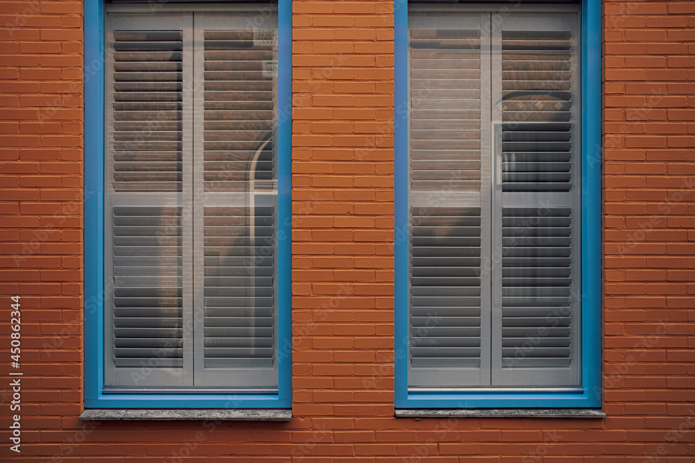blue framed window with blinds in red brick wall
