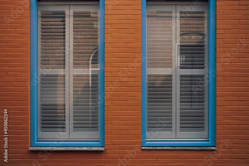 blue framed window with blinds in red brick wall © Stadtrandfoto