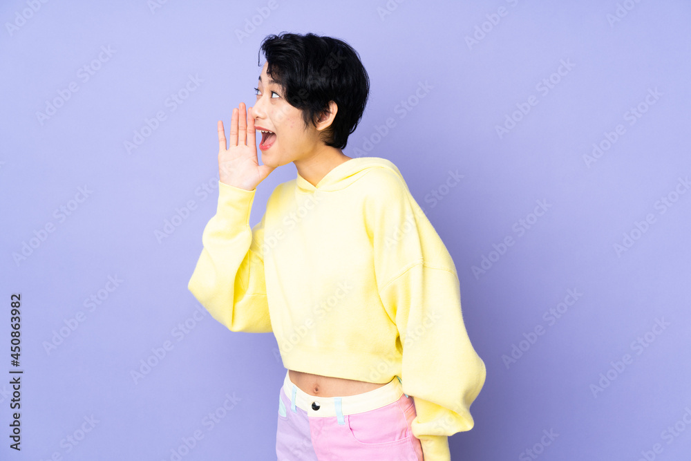 Young Vietnamese woman with short hair over isolated purple background shouting with mouth wide open to the side Young Vietnamese woman with short hair over isolated purple background shouting with mouth wide open to the side