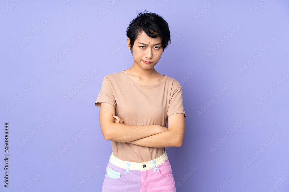 Young Vietnamese woman with short hair over isolated purple background with unhappy expression Young Vietnamese woman with short hair over isolated purple background with unhappy expression