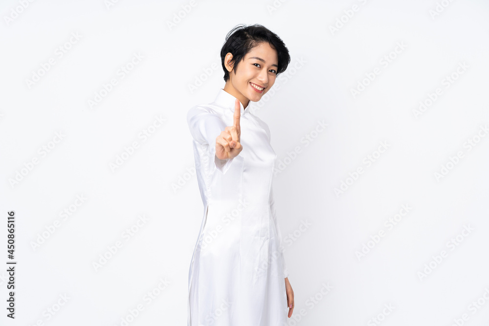 Young Vietnamese woman with short hair wearing a traditional dress over isolated white background showing and lifting a finger Young Vietnamese woman with short hair wearing a traditional dress over isolated white background showing and lifting a finger