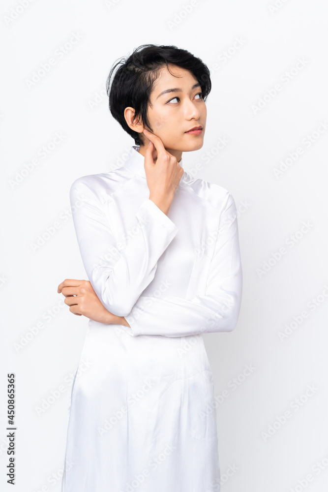 Young Vietnamese woman with short hair wearing a traditional dress over isolated white background Young Vietnamese woman with short hair wearing a traditional dress over isolated white background