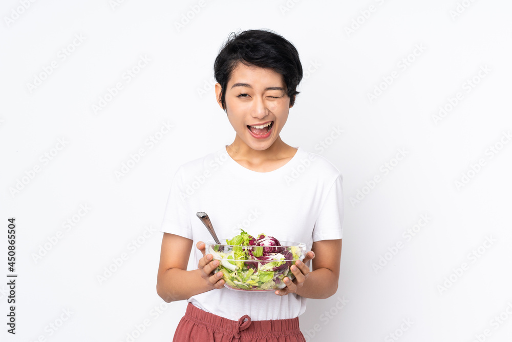 Young Vietnamese woman with short hair holding a salad over isolated background Young Vietnamese woman with short hair holding a salad over isolated background