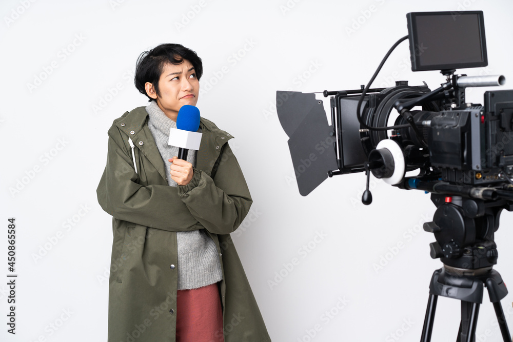 Reporter Vietnamese woman holding a microphone and reporting news making doubts gesture while lifting the shoulders