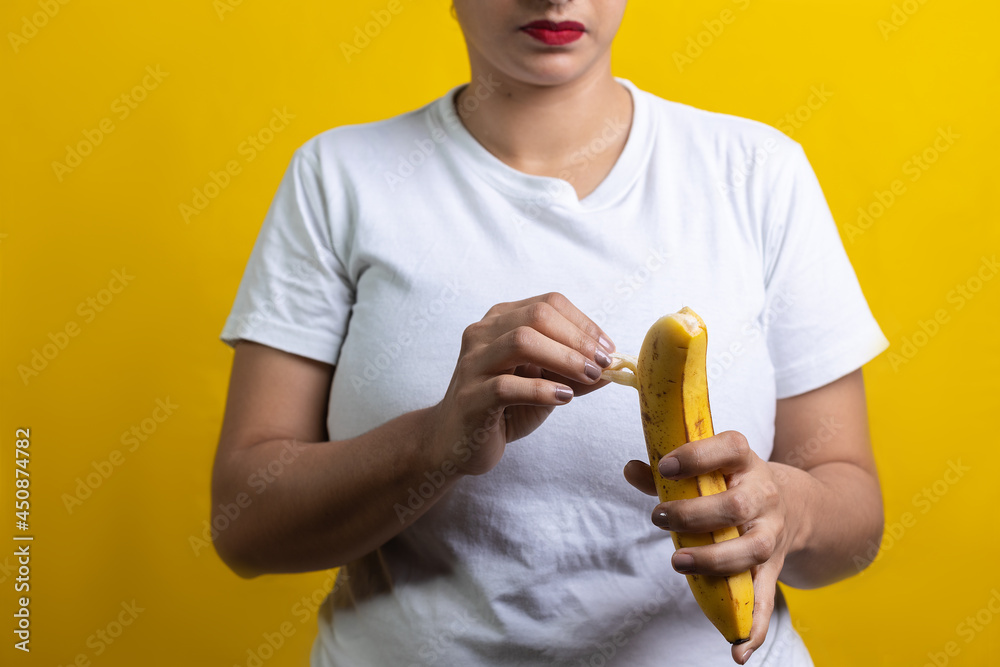 latin woman opening banana to eat, on yellow background latin woman opening banana to eat, on yellow background
