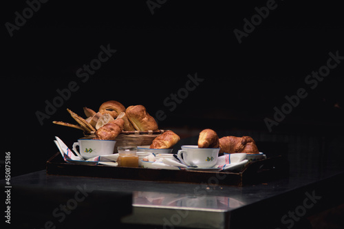 Traditional French breakfast display with croissants, pastry, tea, and coffee