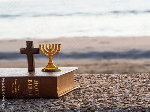 Gold Menorah & Christian cross & bible against  beach and  blue sea photo