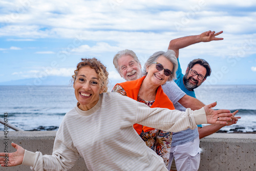 Playful group of family having fun together in outdoor excursion at sea, smiling carefree. Parents, son and daughter-in-law