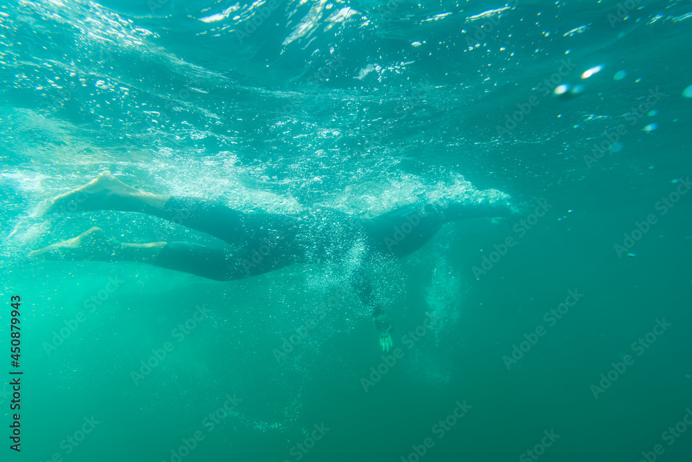 Athlete in a wetsuit swims in a lake