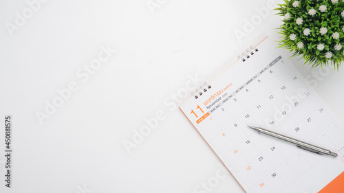 Calendar with vase and pen top view white background on the table copy space