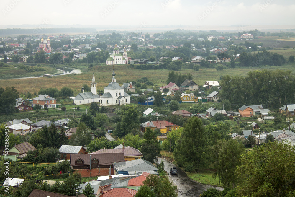 SUZDAL, Vladimir Region, RUSSIA-August, 11,2021: panoramic view of the old town with the roofs of historical buildings and the green foliage of trees on a cloudy summer day