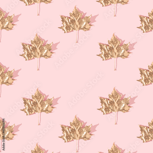 Trendy sunlight autumn pattern made with golden maple leaves on pastel pink background. Minimal nature layout.