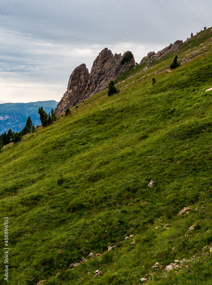 Steep mountain meadow with rock formations in Dolomites mountains in Italy
