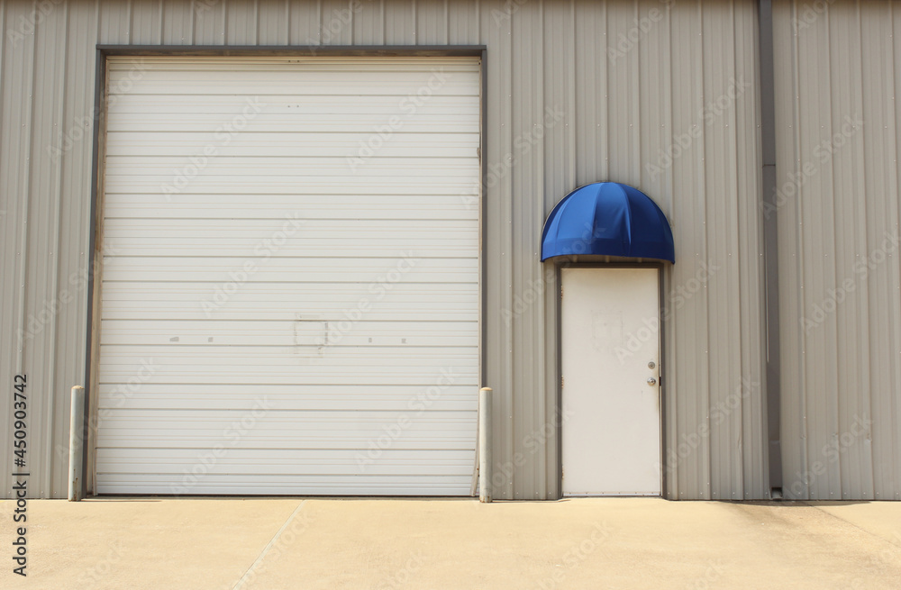 Garage Door on Warehouse and Regular Door With Awning Building Close up Garage Door on Warehouse and Regular Door With Awning Building Close up