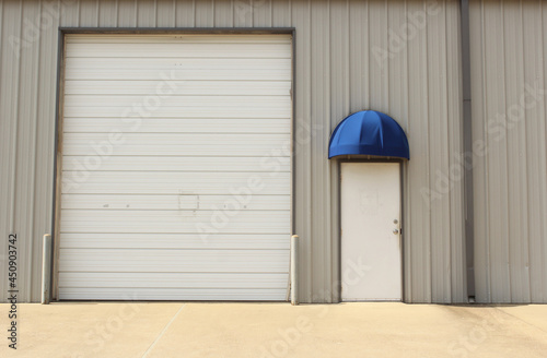Garage Door on Warehouse and Regular Door With Awning Building Close up