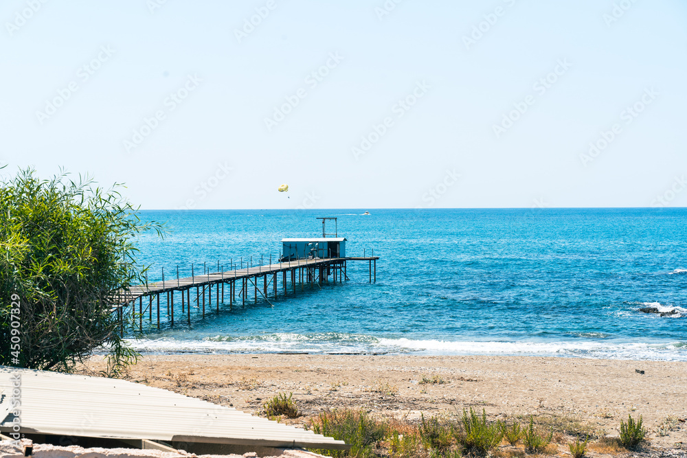 A bridge that goes into the sea where a boat floats and pulls a parachutist behind it.