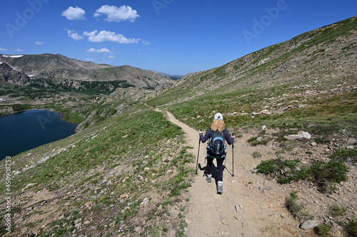 Woman descends King Lake Trail in Indian Peaks Wilderness in Arapaho National Forest, Colorado on clear sunny summer afternoon.