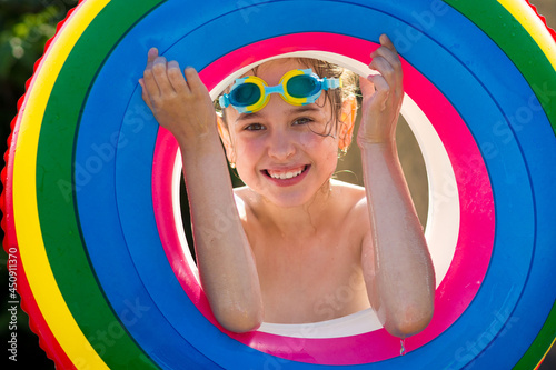 A happy little girl in swimming glasses and a colorful inflatable ring