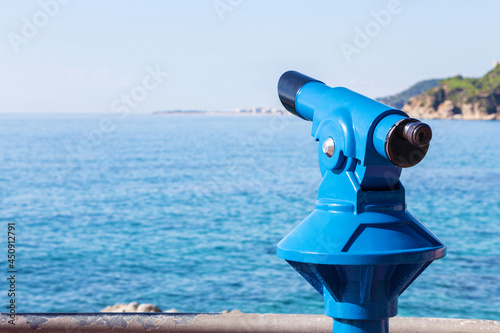 Blue tourist monocular with a beautiful mediterranean landscape in the background on a sunny summer day