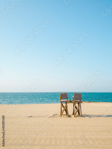 Two Wooden Lifeguard Chairs on the empty beach. Cape Cod Seascape in the early summer morning. Tranquil beachscape with clean sand.