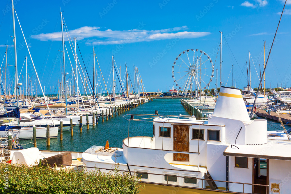 Naklejka premium Summer view of pier with ships, yachts and other boats with ferris wheel in Rimini, Italy
