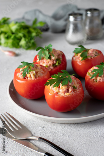 Tomatoes stuffed with ham and cheese on a gray plate on a light gray background