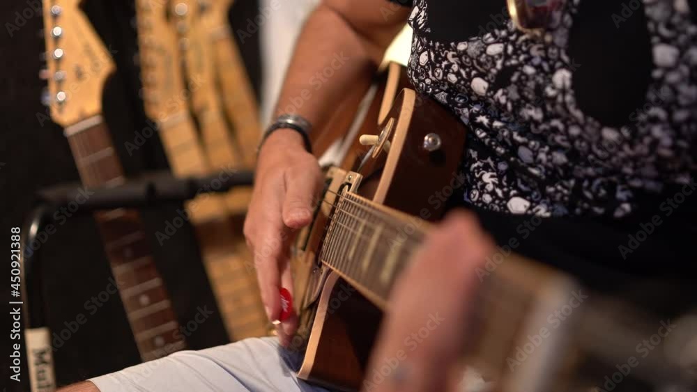 Plano cerrado de musico tocando guitarra eléctrica en un estudio de grabación 