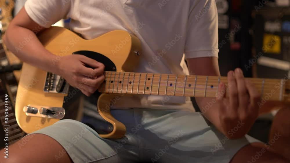 Plano cerrado de musico tocando guitarra eléctrica en un estudio de grabación 