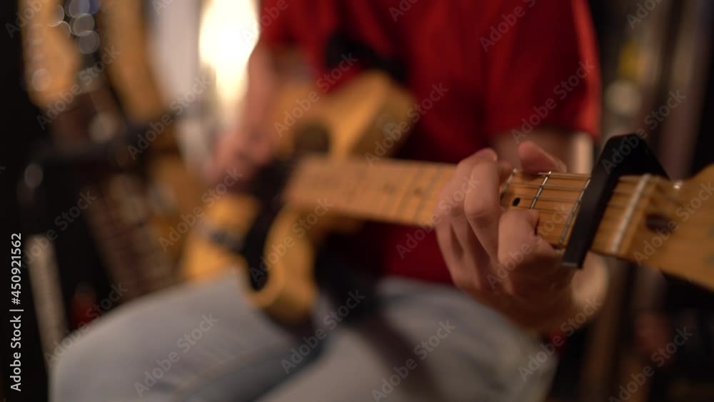 Plano cerrado de musico tocando guitarra eléctrica en un estudio de grabación 