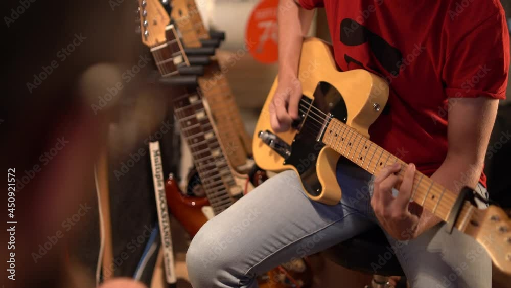 Plano cerrado de musico tocando guitarra eléctrica en un estudio de grabación 