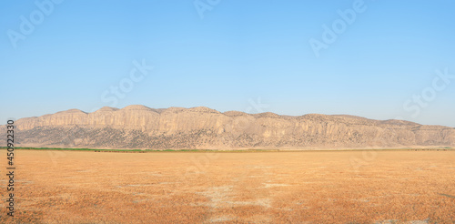 Grasslands of Dasht Arjan. wide panorama with autumn grass field and mountains in background at evening time, Typical autumnal scenery of Fars Province, iran
