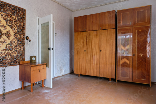 Example of Old Soviet Russian poor interior in Khruschev House. Aged  sideboard, table, chairs, sofa. Shabby floor. Tattered wallpaper on the wall. Paper butterflies as decor. Apartment of pensioners. photo