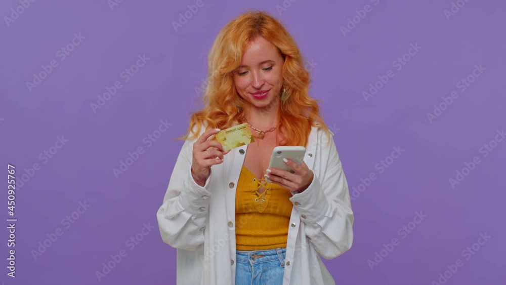 Sincere girl using credit bank card and smartphone while transferring money, purchases online shopping, browsing say wow yes, found out great big win, winner gesture. Young woman on purple background Sincere girl using credit bank card and smartphone while transferring money, purchases online shopping, browsing say wow yes, found out great big win, winner gesture. Young woman on purple background