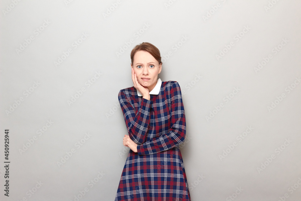 Obraz premium Portrait of sad unhappy shocked young woman touching cheek with hand