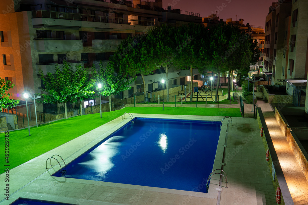 Swimming pool at night with some lights and greens around it