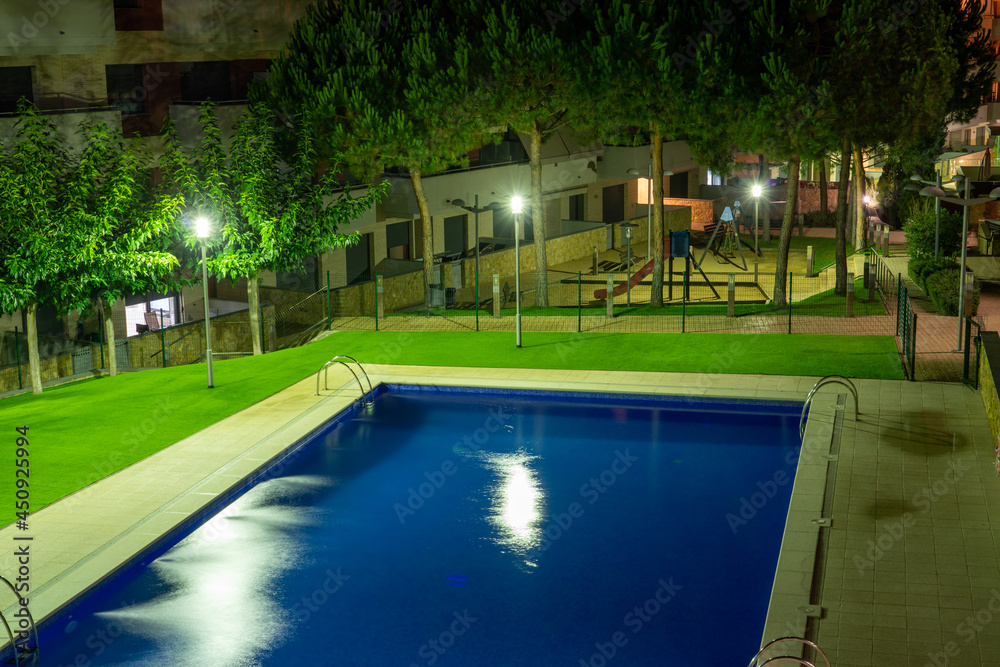 Swimming pool at night with some lights and greens around it Swimming pool at night with some lights and greens around it