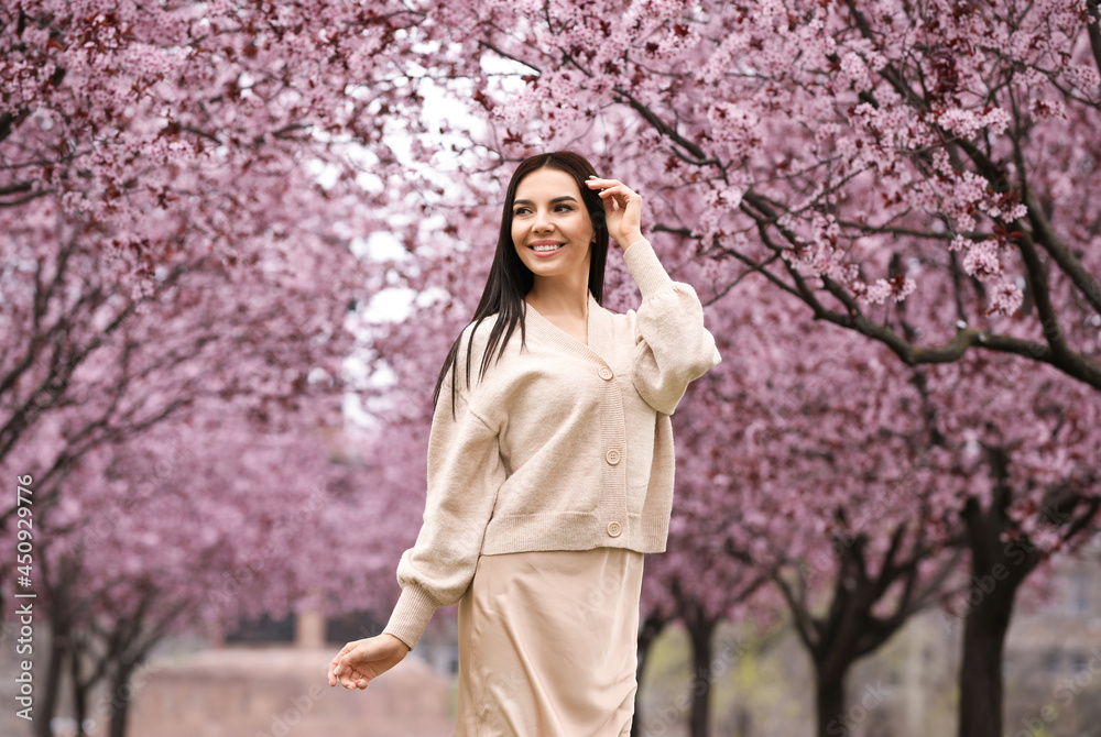 Pretty young woman in park with blooming trees. Spring look Pretty young woman in park with blooming trees. Spring look