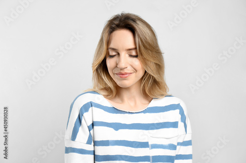 Portrait of happy young woman with beautiful blonde hair on light background