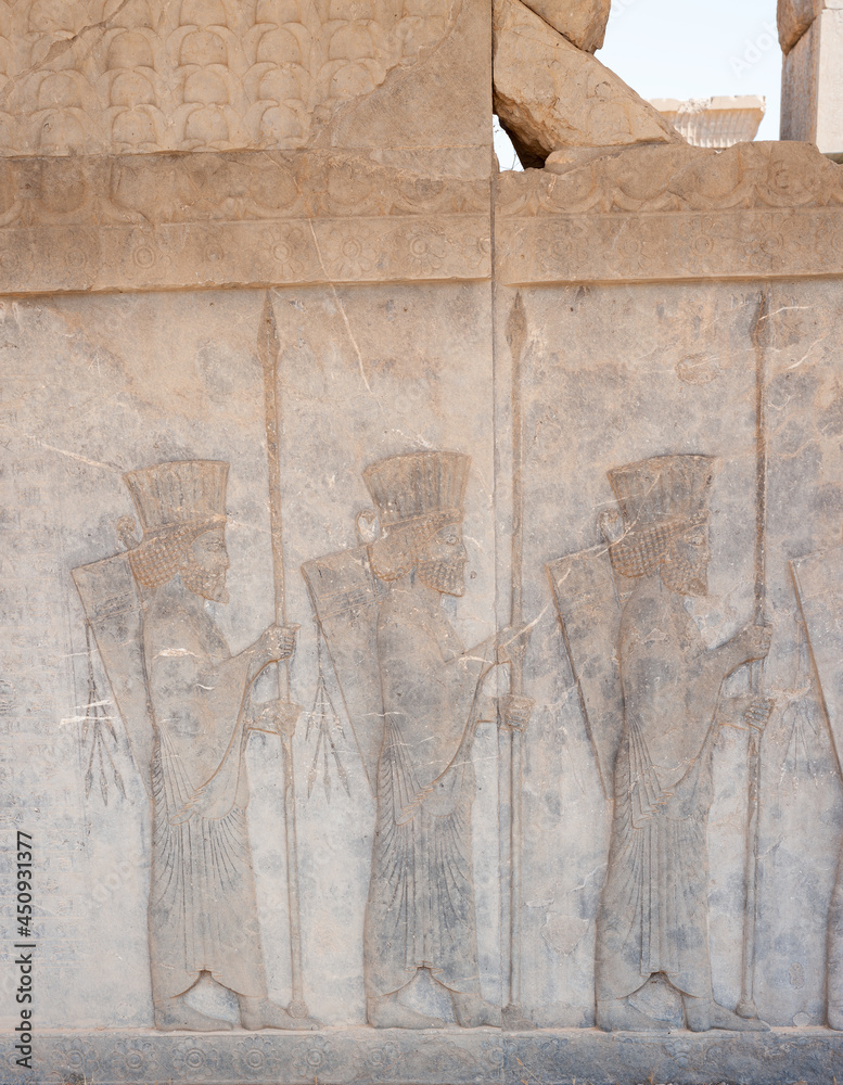 Soldiers of historical empire with weapon in hands. Stone bas-relief in ancient city Persepolis, Iran. Capital of the Achaemenid Empire (550 - 330 BC). UNESCO declared Persepolis a World Heritage Site