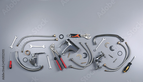 Parts of water tap and plumber tools on grey background, flat lay