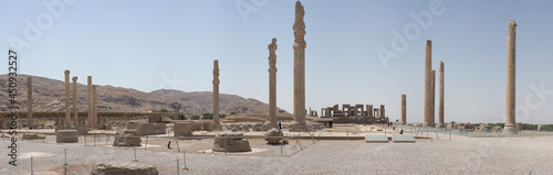 Ruins of Apadana and Tachara Palace behind stairway with bas relief carvings in Persepolis UNESCO World Heritage Site against cloudy blue sky in Shiraz city of Iran.
