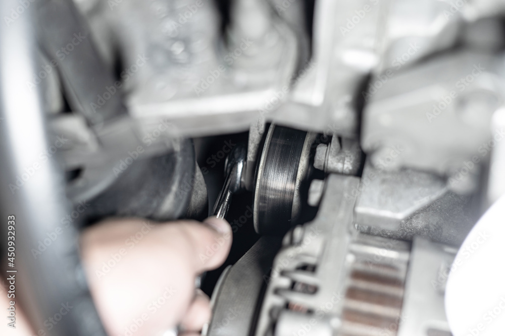 Belt Tension Pulley of car engine and a man use wrench adjust and Replacement of spare parts in engine room Belt Tension Pulley of car engine and a man use wrench adjust and Replacement of spare parts in engine room